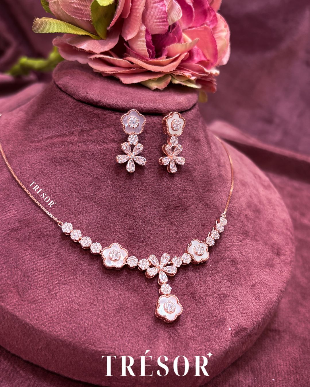 Trésor jewelry set with necklace and earrings on a pink velvet cushion.